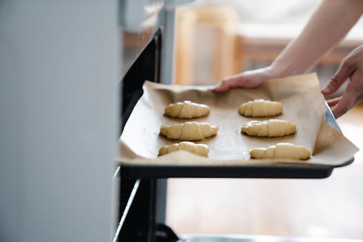 Plaque de cuisson avec des croissants en pâte feuilletée prête à être enfournée dans un four.