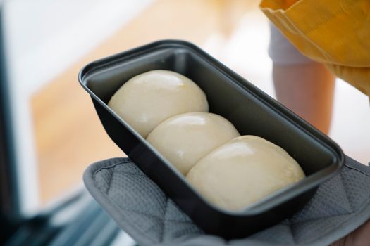 Pâte à brioche moelleuse en trois boules dans un moule, prête à être cuite.