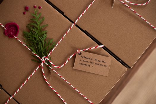 Cadeaux soigneusement emballés dans des boîtes en carton avec une décoration naturelle et un ruban rouge et blanc.
