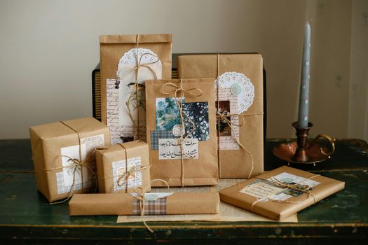 Cadeaux soigneusement emballés dans du papier kraft, décorés de motifs et de ficelles, sur une table en bois.